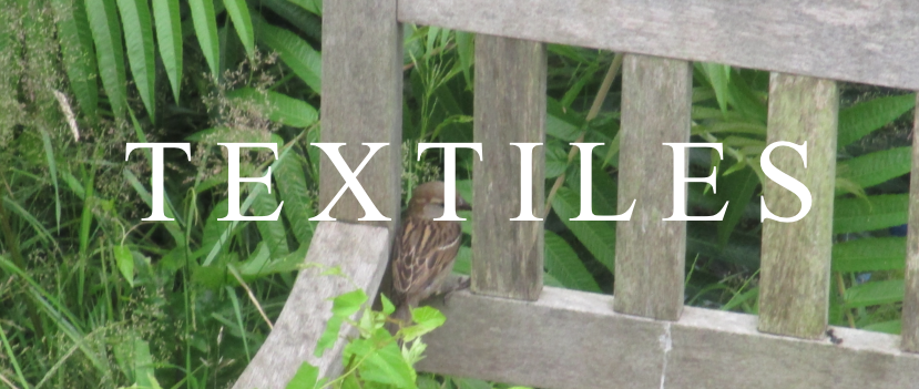 photo of a sparrow on the back of a chair with leaves and plants all around. white text over top says TEXTILES.